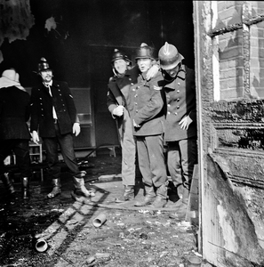 831219 Afbeelding van enkele brandweermannen bij het blussen van een brand in de speelzaal van de kleuterschool Het ...